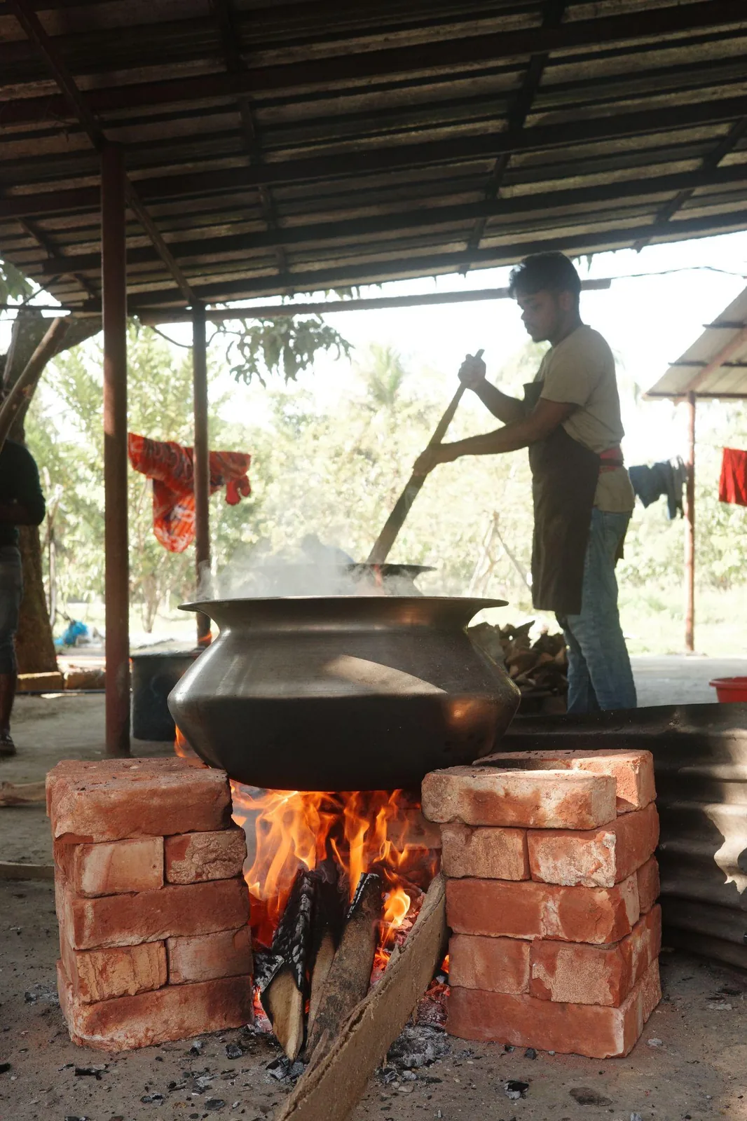 A large cooking pot set over a brick wood fire
