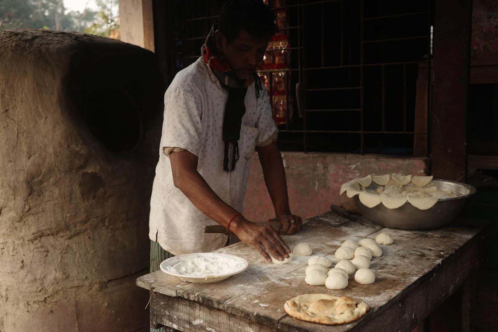Dough being rolled and portioned for paratha on a stone counter
