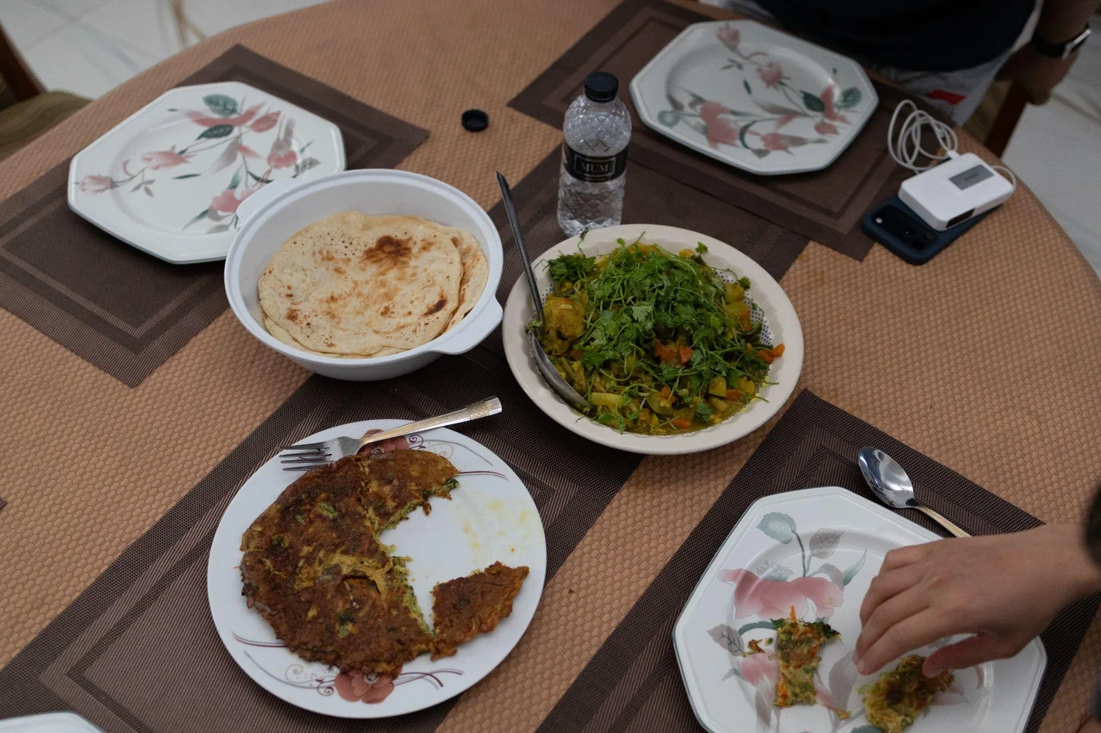 The dining table laid with curries, greens, rice and paratha