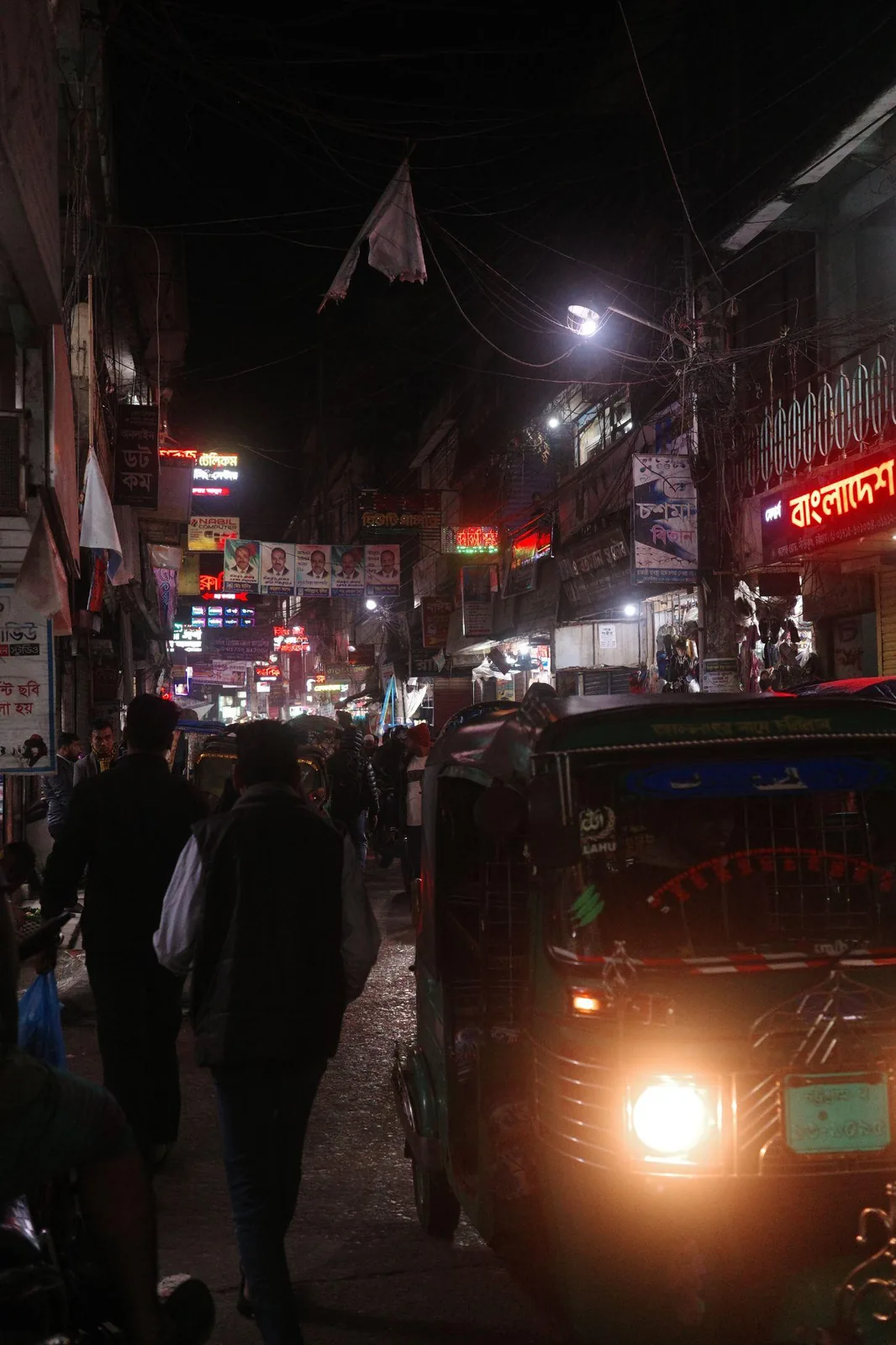 A street at night, lit by the headlight of a passing rickshaw